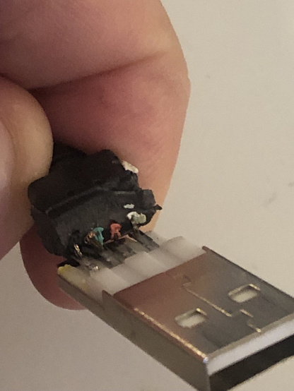 USB-A plug seen from the bottom side. Plastic between plug and cable partly removed so you can see the solder connections and part of the cables. Colors from left to right:
Black, Green, Red, White