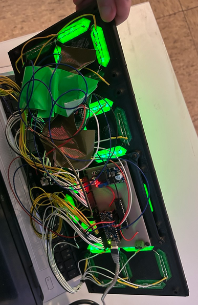 7-Segment-Anzeige des letzten Bildes von hinten. Die Segmente sind über je 5 Standard-LEDs realisiert. Dahinter ein ziemlicher Wust aus einzelnen Kabeln, welche auf eine offenbar selbstbemachte Platine mit Arduino und ICs zusammenlaufen. Teile der Elektronik sind in Gewebeband eingepackt.