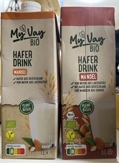 Getränkekartons MyVay Bio Hafer-Drink Mandel. Die alte Packung ist in einem Orange-Braun gehalten, nie neue in einem Rot-Braun mit mehr Deko-Elementen.