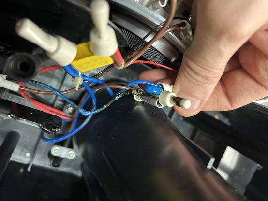 Innenleben eines Gerätes. Man sieht diverse blaue, rote und braune Kabel in verschiedenen Dicken. Sie sind über Crimp-Drahtmuttern verbunden. Die Isolierung einiger Kabel und Teile der inneren Gehäusestruktur sind geschmolzen, teils liegt das Kupfer frei.