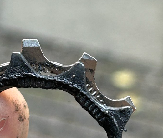 Zwei 10T-Ritzel aus Steckkränzen.
Hinten: Silber mit breiten Zähnen
Vorne: Schwarz, die Zähne sind stark abgenutzt und teils oben spitz.