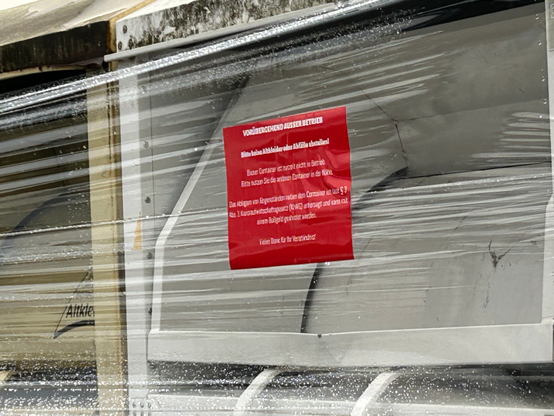 Kleidercontainer in Klarsichtfolie. Roter Zettel auf Folie.

Vorübergehend außer Betrieb!
Mit weiteren Hinweisen, welche Strafen drohen, wenn man was daneben stellt.