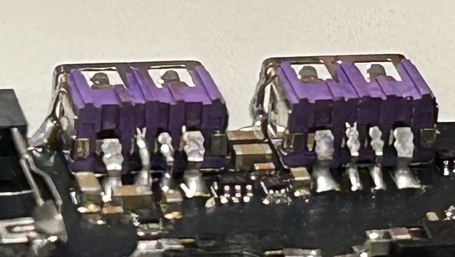 USB A 2.0 Buchsen, welche überkopf auf eine schwarze, mit SMD-Kleinkram bestückte Platine gelötet sind. Die Kontakte sind umgebogen und mit "ganz tollen" Lötstellen verbunden.