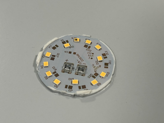 Rundes LED-Board einer E27-Lampe mit 12 LEDs. Eine hat mehrere schwarze Punkte im Phosphor.